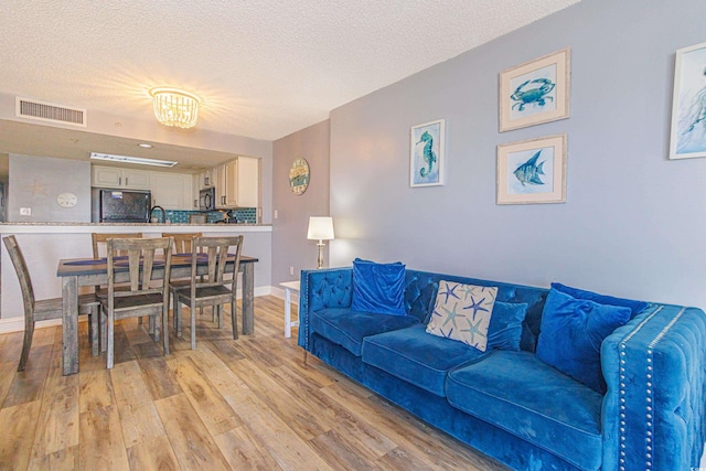 205 74th Ave N Unit 702, Myrtle Beach, SC 29572 - living area with light wood-type flooring, a textured ceiling, and a chandelier