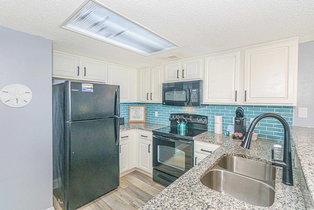 205 74th Ave N Unit 702, Myrtle Beach, SC 29572 - kitchen featuring black appliances, a textured ceiling, light wood-style floors, light stone countertops, and white cabinetry
