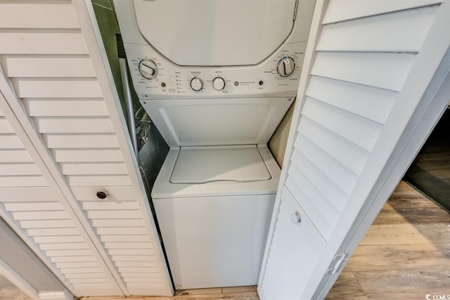 laundry area with light wood-style floors, stacked washer / dryer, and laundry area