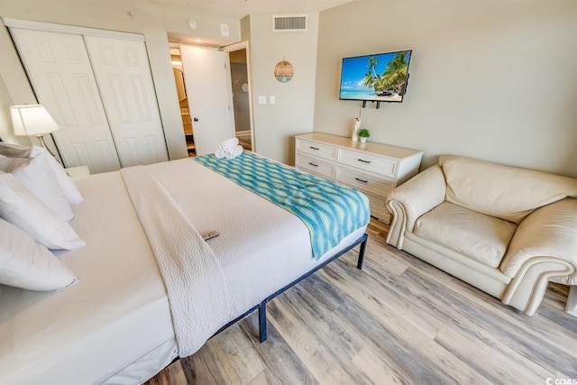 bedroom with a closet, visible vents, and light wood finished floors