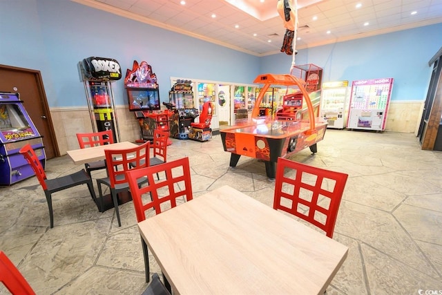 playroom featuring recessed lighting, a wainscoted wall, crown molding, and a high ceiling