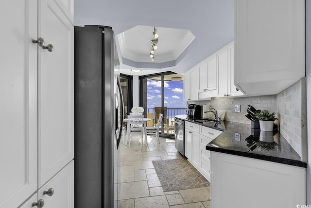 kitchen featuring stainless steel appliances, stone tile flooring, a raised ceiling, decorative backsplash, and white cabinets