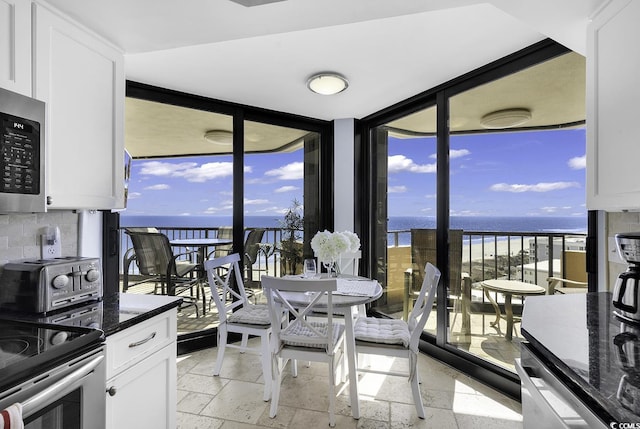 kitchen with dark stone countertops, a water view, and white cabinetry