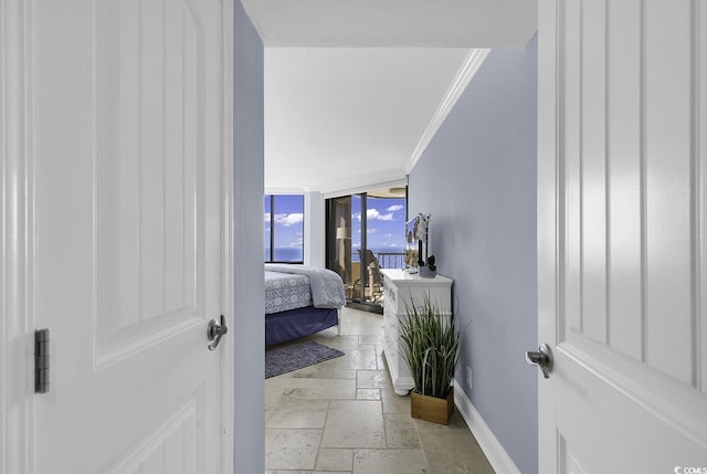 bedroom with baseboards, crown molding, a wall of windows, and stone tile floors