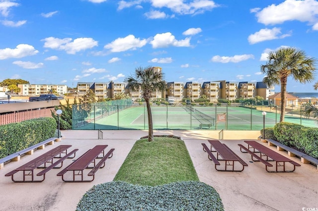 view of community featuring a tennis court, fence, and a residential view