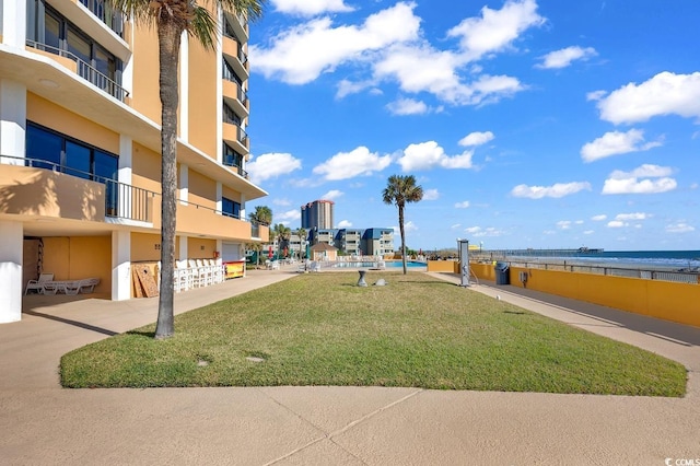 view of home's community featuring a water view, a lawn, and fence