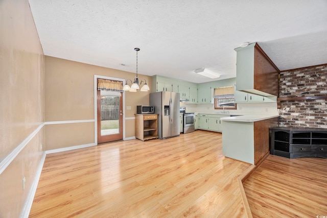 kitchen with stainless steel appliances, light countertops, an inviting chandelier, light wood-style floors, and a peninsula