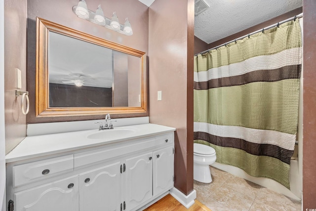 bathroom with a textured ceiling, toilet, visible vents, vanity, and tile patterned floors