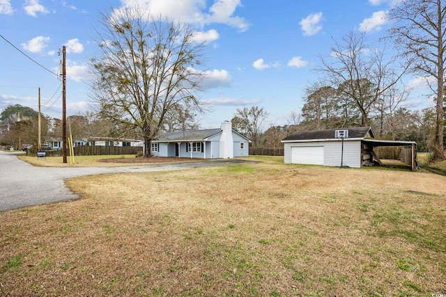 view of yard with an outbuilding, driveway, a detached garage, and fence