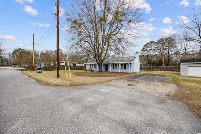 view of front of property with a chimney, fence, aphalt driveway, and an outdoor structure