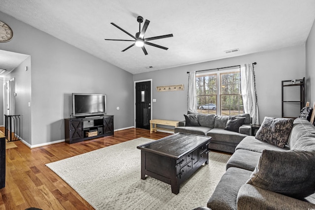 living room featuring visible vents, baseboards, lofted ceiling, ceiling fan, and wood finished floors