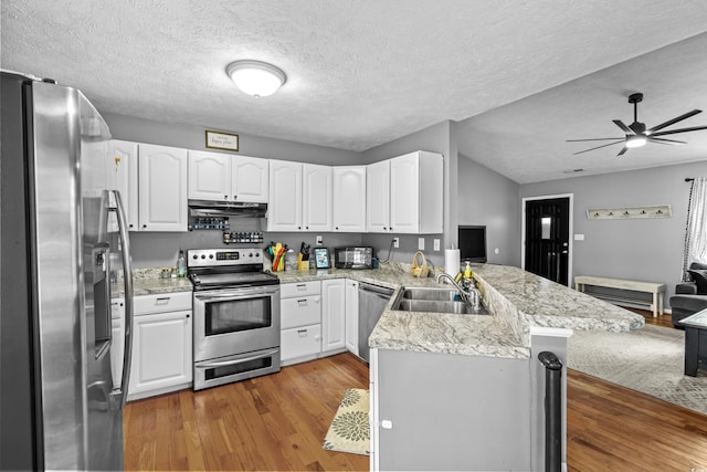 kitchen with appliances with stainless steel finishes, white cabinetry, a sink, a peninsula, and under cabinet range hood