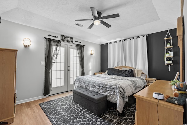 bedroom featuring light wood-type flooring, french doors, visible vents, and a textured ceiling