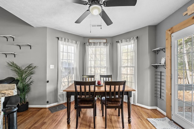 dining room with a healthy amount of sunlight, visible vents, light wood-style flooring, and baseboards