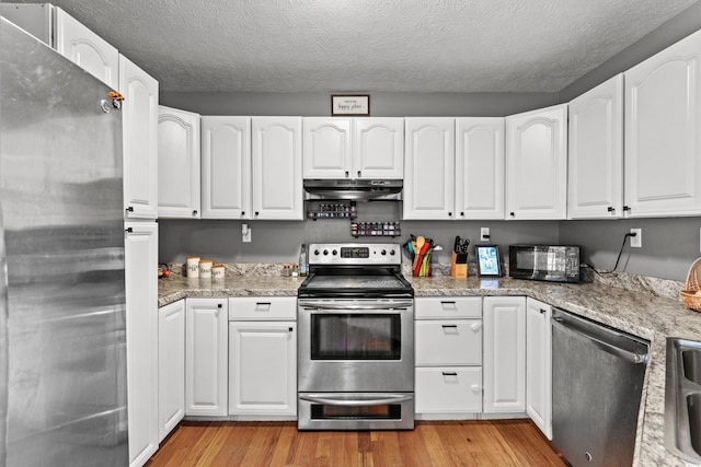 kitchen featuring white cabinets, under cabinet range hood, and stainless steel appliances