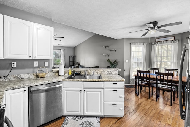 kitchen with a peninsula, a sink, light wood-style floors, white cabinets, and stainless steel dishwasher