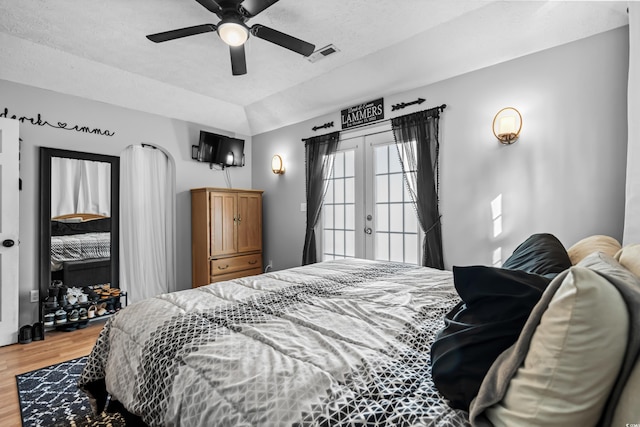 bedroom featuring lofted ceiling, ceiling fan, wood finished floors, visible vents, and french doors