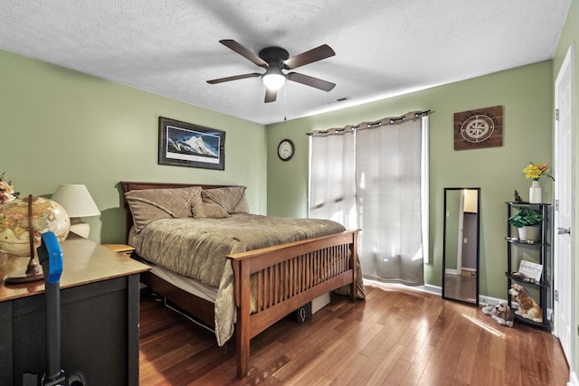 bedroom with dark wood-style flooring, visible vents, a textured ceiling, and baseboards