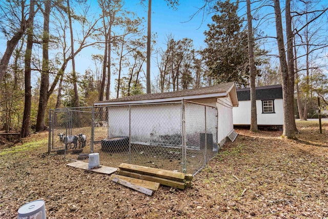 exterior space with an outbuilding, roof with shingles, and exterior structure