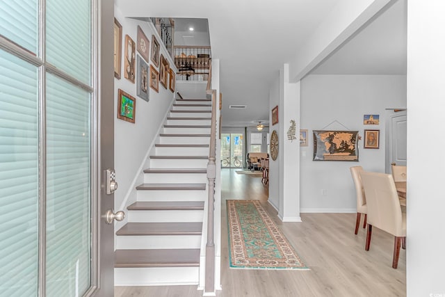 foyer featuring a ceiling fan, stairway, baseboards, and wood finished floors