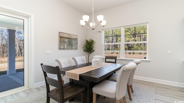 dining space with light wood finished floors, baseboards, and a notable chandelier