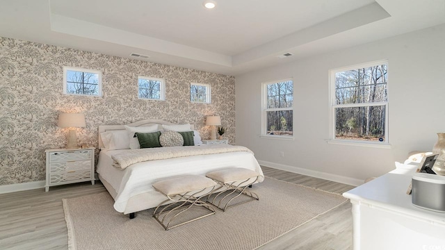 bedroom featuring baseboards, wallpapered walls, and a raised ceiling