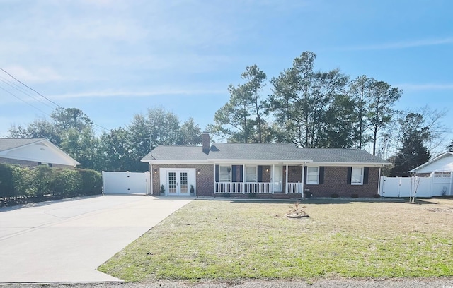 ranch-style house featuring brick siding, concrete driveway, french doors, a gate, and a front lawn