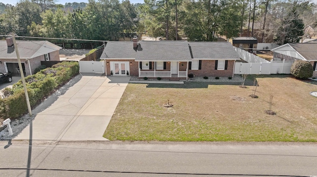 ranch-style house featuring driveway, fence, french doors, a front lawn, and brick siding