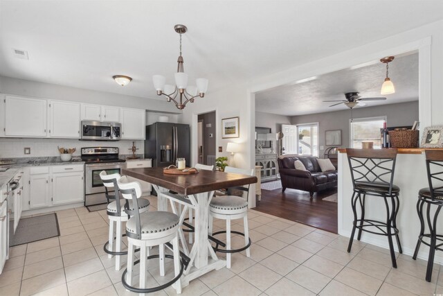 kitchen with white cabinets, light tile patterned floors, visible vents, and stainless steel appliances