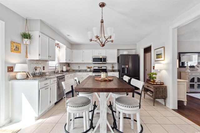 kitchen featuring light tile patterned floors, tasteful backsplash, stainless steel appliances, white cabinetry, and a sink