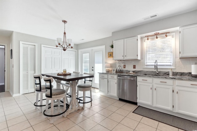 kitchen with light tile patterned floors, a sink, white cabinets, dishwasher, and tasteful backsplash