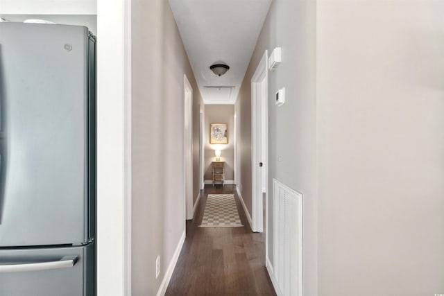 hallway with attic access, visible vents, dark wood finished floors, and baseboards