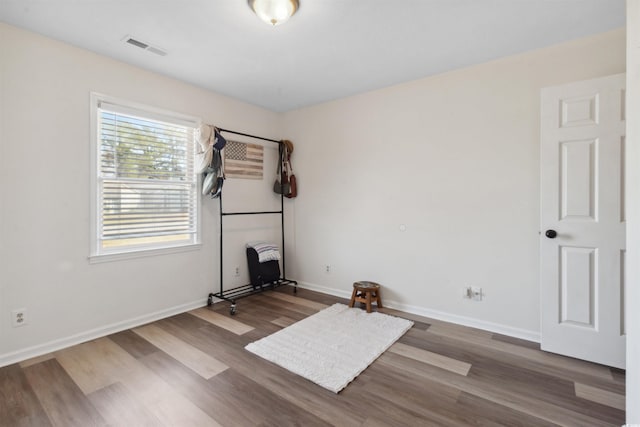 empty room with baseboards, visible vents, and wood finished floors