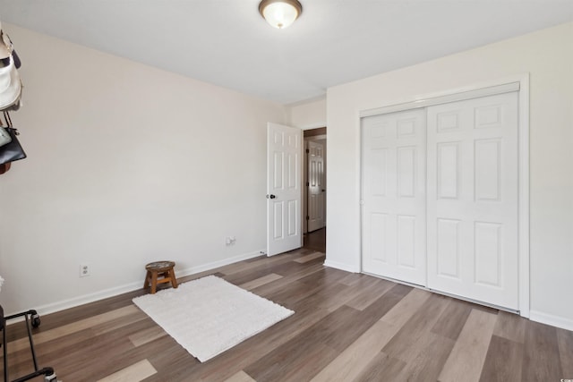 unfurnished bedroom with a closet, baseboards, and wood finished floors