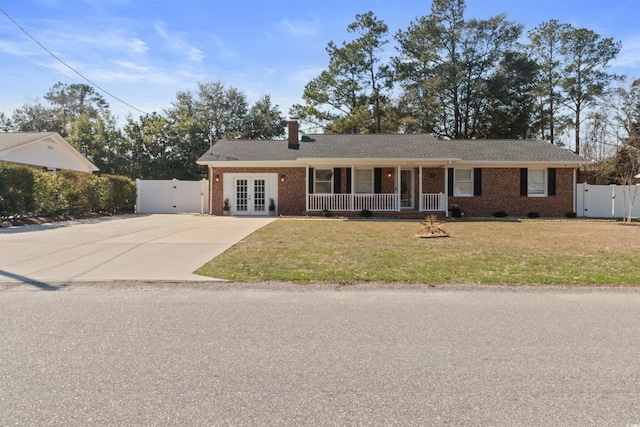 ranch-style house featuring concrete driveway, a gate, french doors, a front lawn, and brick siding