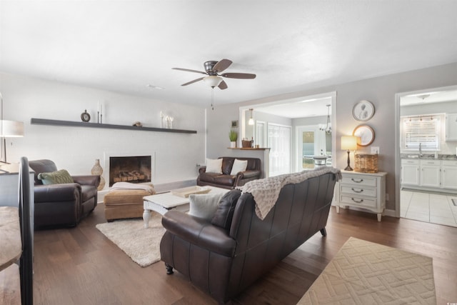 living room featuring a brick fireplace, a healthy amount of sunlight, and wood finished floors