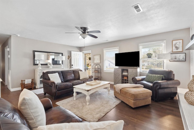 living area with dark wood-style floors, ceiling fan, visible vents, and baseboards