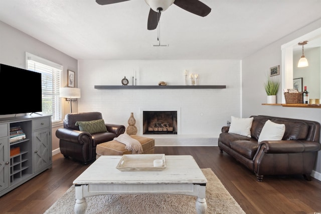 living room featuring a brick fireplace, dark wood finished floors, and a ceiling fan