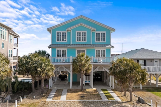 raised beach house with driveway, metal roof, and a carport