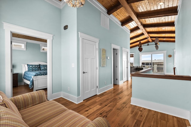 living area with baseboards, wood ceiling, wood finished floors, vaulted ceiling with beams, and a chandelier