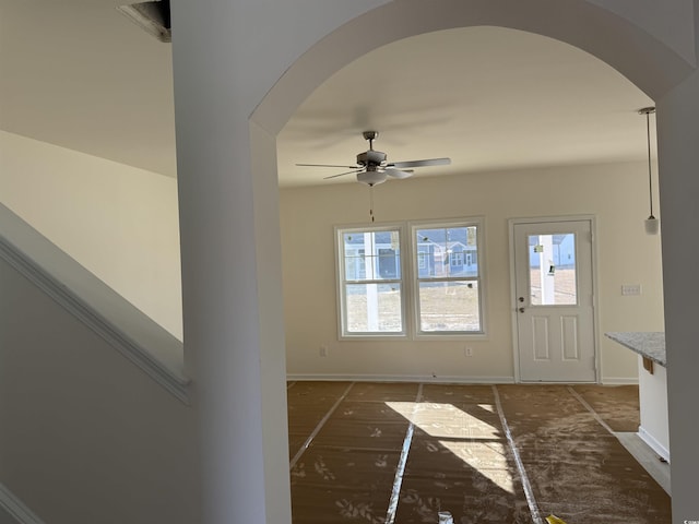 entrance foyer featuring arched walkways, a ceiling fan, and baseboards