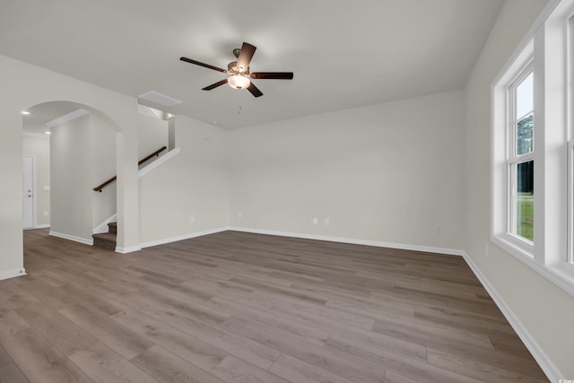 1064 Jase Dr, Longs, SC 29568 - unfurnished living room featuring wood finished floors, arched walkways, a ceiling fan, baseboards, and stairs