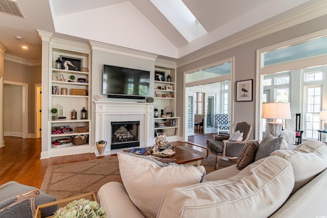 living area featuring visible vents, a tiled fireplace, ornamental molding, wood finished floors, and built in shelves