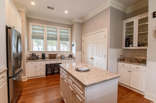 kitchen featuring dark wood-type flooring, white cabinetry, visible vents, and stainless steel fridge with ice dispenser