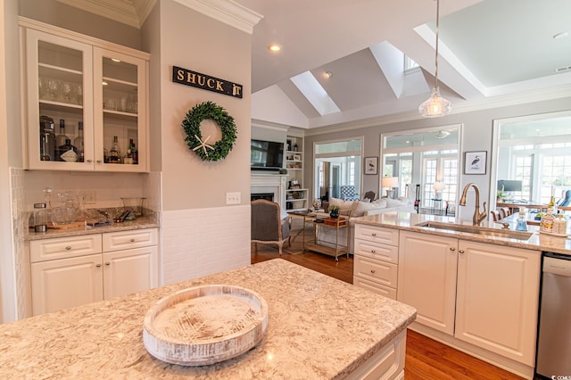 kitchen featuring light stone counters, a fireplace, a sink, dishwasher, and glass insert cabinets