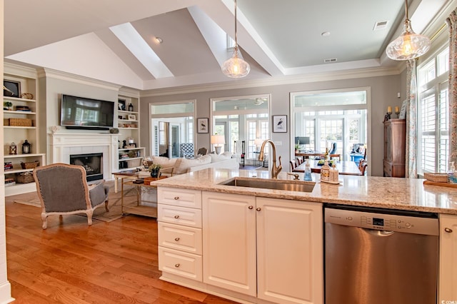 kitchen featuring dishwasher, light wood-style flooring, light stone countertops, a fireplace, and a sink