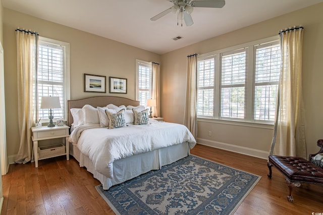 bedroom with a ceiling fan, baseboards, visible vents, and wood finished floors