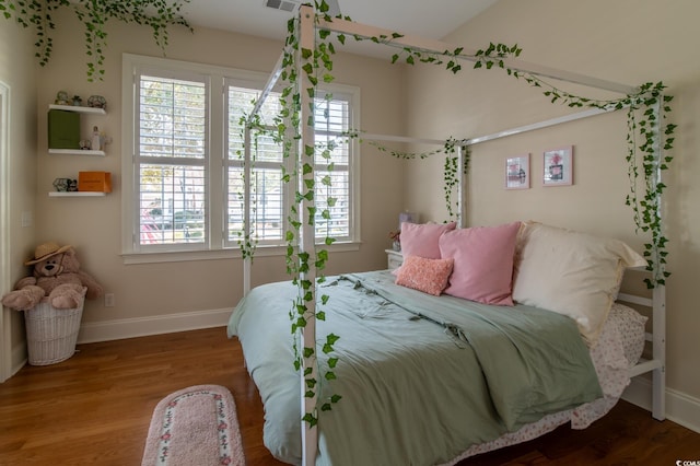 bedroom featuring visible vents, baseboards, and wood finished floors