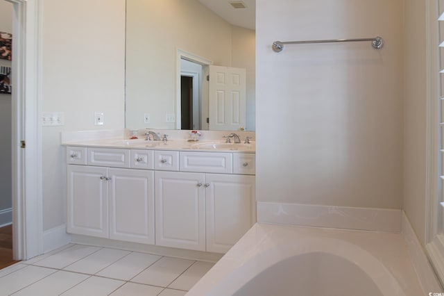 full bath featuring a tub to relax in, double vanity, a sink, and tile patterned floors