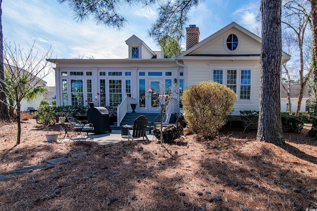 rear view of property featuring a patio and a chimney